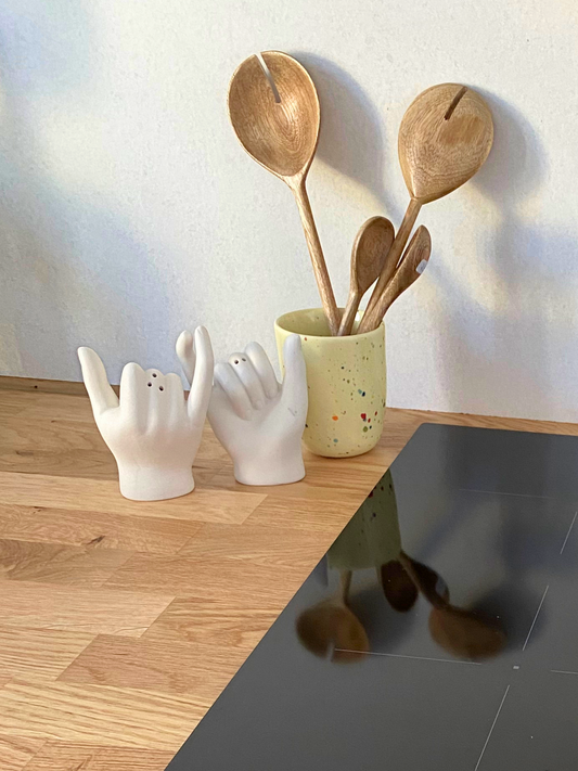 DOIY Salz- und Pfefferstreuer „Pinky Swear“ – zwei weiße Keramikstreuer in Form von Händen, die sich mit den kleinen Fingern berühren, auf einem Küchentisch. Dolomite