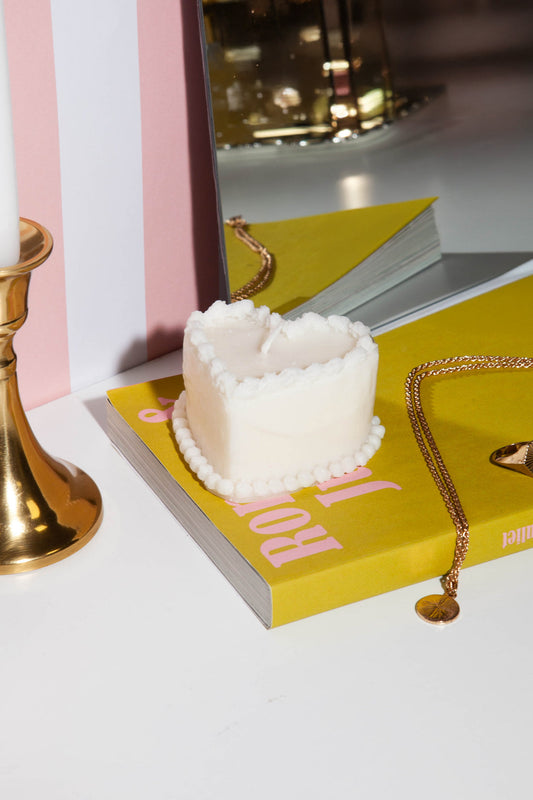 DOIY Kerze Torte „Sweetie“ dekorativ auf einem Buch und mit einer goldenen Kerze im Hintergrund präsentiert.